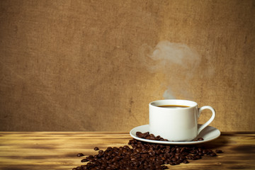 Coffee beans and coffee in white cup on wooden table opposite a