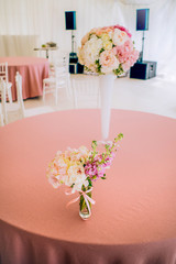 The decor table with pink tablecloth and bouguet of roses