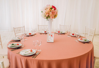 The decor table with pink tablecloth and bouguet of roses