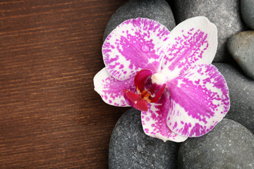Spa stones and orchid on wooden background