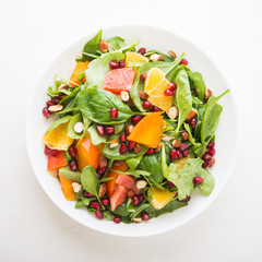 Fresh salad with fruits and greens on white background top view. Healthy food.