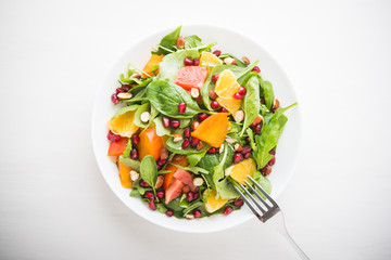 Fresh salad with fruits and greens on white background top view. Healthy food.