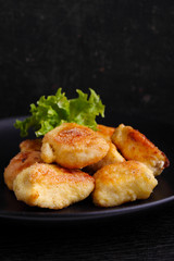 chicken nuggets in a black plate on a black background