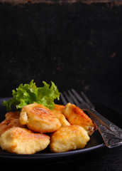 chicken nuggets in a black plate on a black background