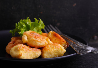 chicken nuggets in a black plate on a black background