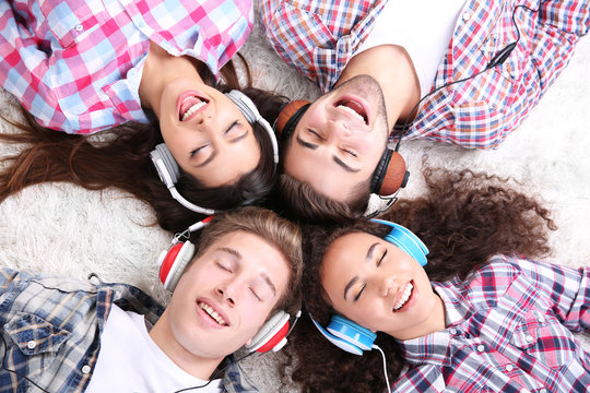 Two teenager couples listening to music with headphones on a carpet