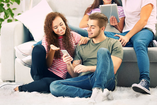 Teenager couple listening to music with mobile phone in living room