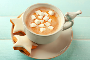 Cup of hot cacao with marshmallow and cookies on blue table