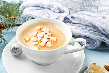Cup of hot cacao with marshmallow, cookies and warm scarf on blue table