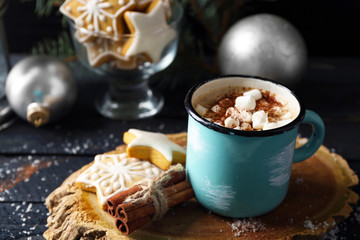 Mug of hot cacao with marshmallow and cookies on black table
