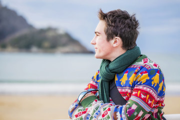 Young attractive man standing on the shore and looks at the sea.