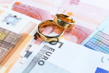 Golden wedding rings on euro banknotes background. Marriage of convenience