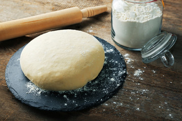 Fresh prepared dough on a wooden board, close up
