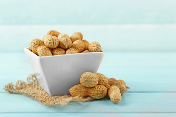 Peanuts in the bowl on blue wooden background