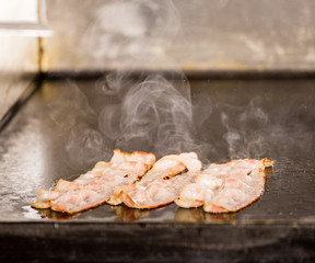 Closeup of Tasty Fried Bacon Strips on Grilling Panel