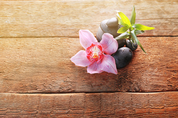 Spa stones with bamboo and pink orchid on wooden background