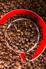 A red cup of coffee bean on the coffee beans background. Top view