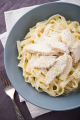 Pasta fettuccine alfredo with chicken and parmesan on dark canvas background top view. Italian cuisine.
