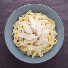 Pasta fettuccine alfredo with chicken and parmesan on dark canvas background top view. Italian cuisine.
