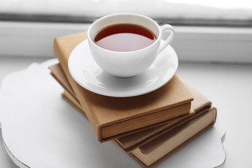 Cup of tea, book  and warm knitted plaid on windowsill, close up
