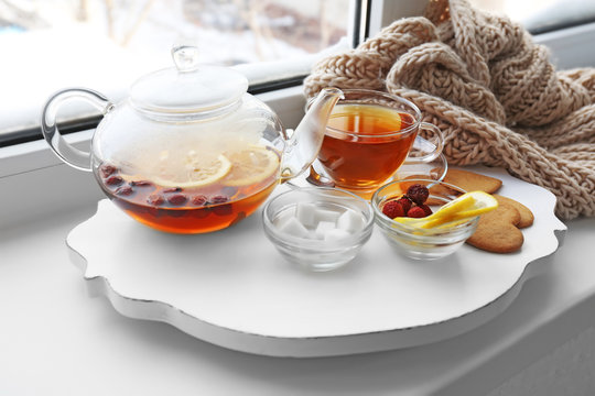 Tea set on a white wooden mat on the windowsill