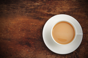 Porcelain cup of tea with milk on wooden background