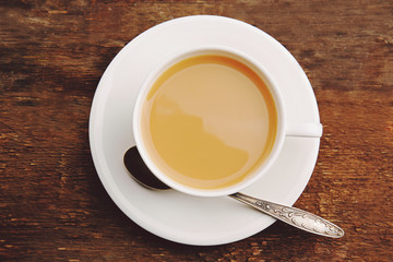 Porcelain cup of tea with milk on wooden background