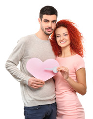 Young couple in love holding paper pink heart and key, isolated on white