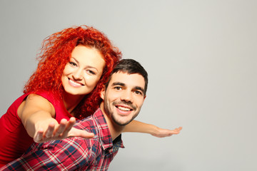 Young couple in love having fun on grey background