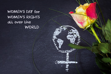 Rose and a chalk drawn female sign with earth globe on a blackboar, text Womens Day, Womenss Rights