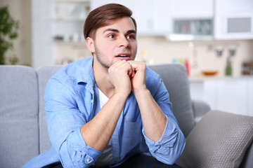 Young handsome man watching TV on a sofa at home