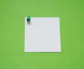 close up of a note paper with push pin on green background