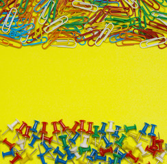 Colorful paper clip and pin isolated on yellow background