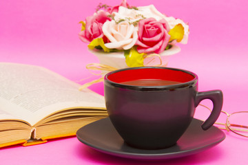 Cup of coffee with book isolated on pink background