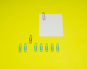 note with color paper clip isolated on yellow background