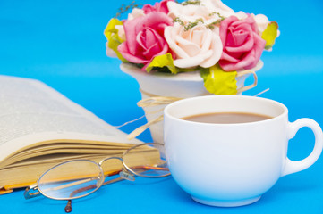 Cup of coffee with book isolated on blue background