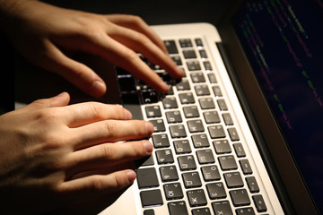 Hacker using laptop, closeup