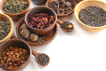 Variety of dry tea in pots and wooden spoons isolated on white, copy space