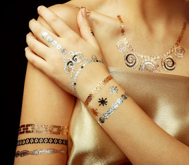 Young blonde girl with golden and silver flash tattoo on black background