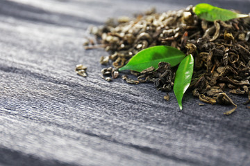 Granulated tea with green leaves on grey background