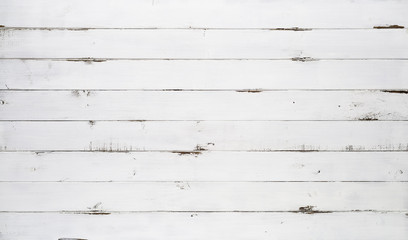 Distressed white wood texture background viewed from above. The wooden planks are stacked horizontally and have a worn look. This surface would be great as design element for a wall, floor, table etc…