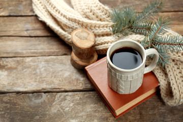Cup of hot drink with knitted warm winter scarf on old wooden table