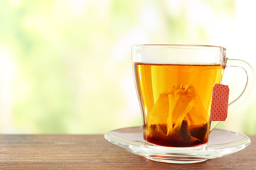 Glass cup with tea bag on wooden table, close up