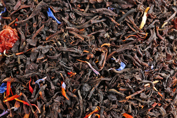 Dry tea with pieces of fruits and flower petals on background