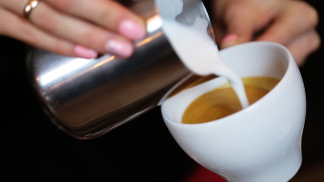  hands of barista making latte or cappuccino coffee pouring milk making latte art.