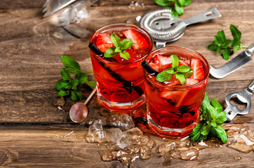 Red drink with ice, mint leaves and strawberry cocktail