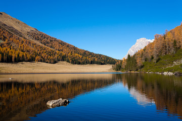 Fototapeta na wymiar Reflections on water, autumn panorama from mountain lake
