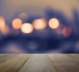 Obraz premium wood table top on abstract background with bokeh defocused lights and shadow from cityscape at night, vintage or retro color tone
