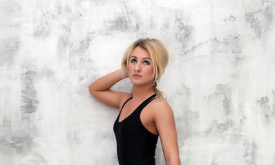 Фитнес, спорт, мускулистая загорелая красивая блондинка девушка в бикини позирует  в студии на фоне белой кирпичной стены.
