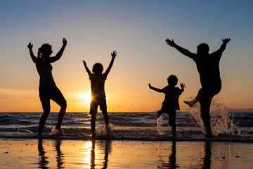 Fototapeta premium Silhouette of happy family who playing on the beach at the sunse